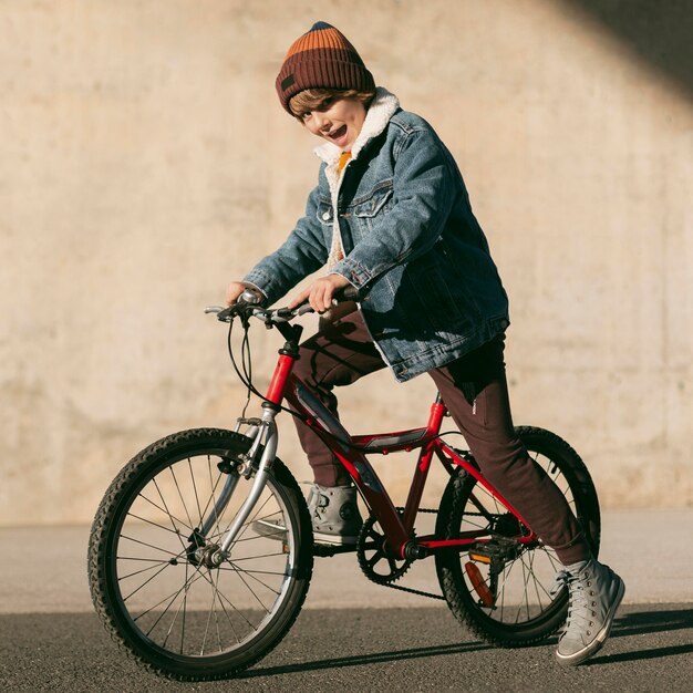 Vista lateral del niño en bicicleta al aire libre divirtiéndose