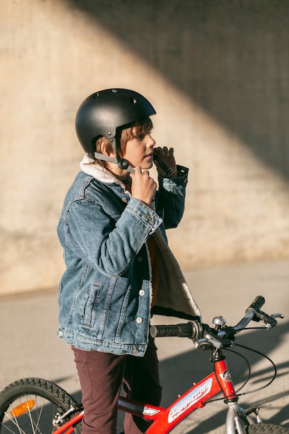 Vista lateral del niño con casco de seguridad en su bicicleta