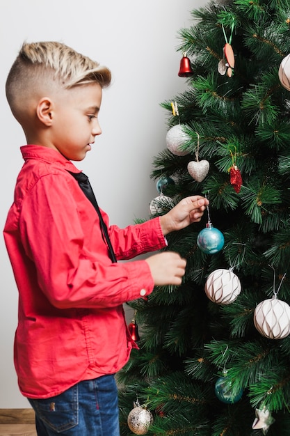 Vista lateral de niño decorando árbol de navidad