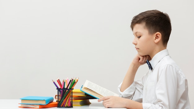 Vista lateral, niño joven, lectura