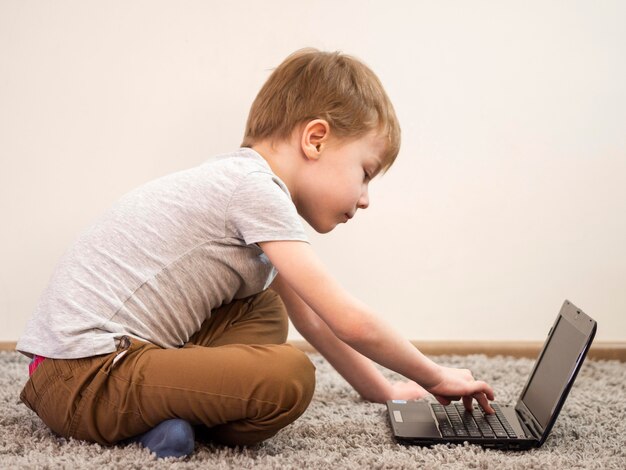 Vista lateral niño jugando en la computadora portátil