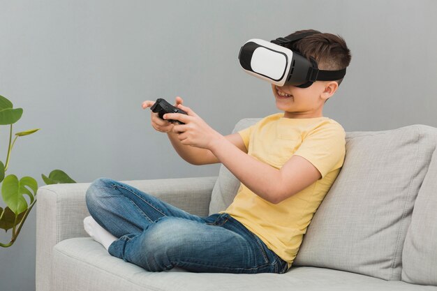 Vista lateral del niño jugando videojuegos con casco de realidad virtual