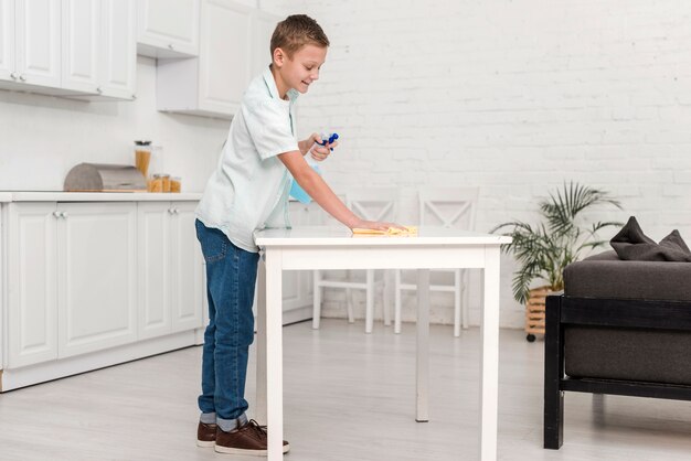 Vista lateral del niño limpiando la mesa