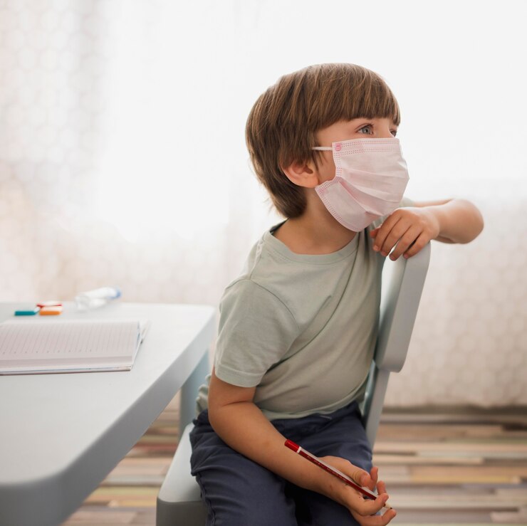 Foto gratuito vista lateral del niño con máscara médica prestando atención al tutor en casa
