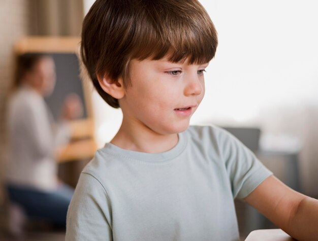 Vista lateral del niño que recibe tutoría en casa