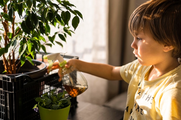 Vista lateral del niño regando las plantas.