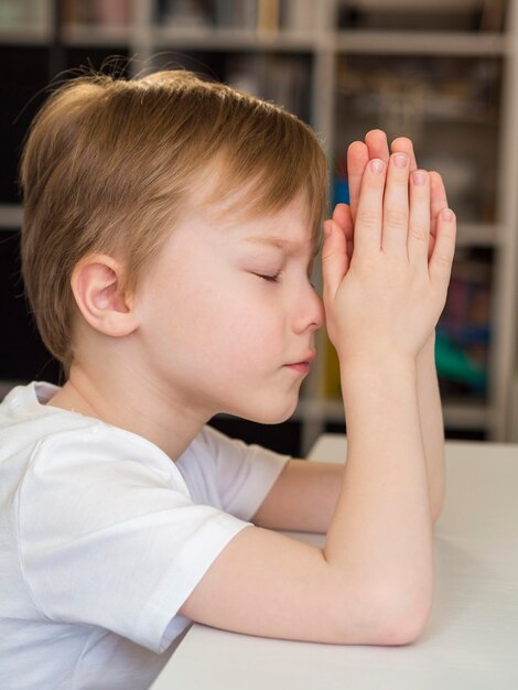 Vista lateral del niño rezando