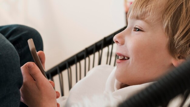 Vista lateral del niño sonriente con smartphone