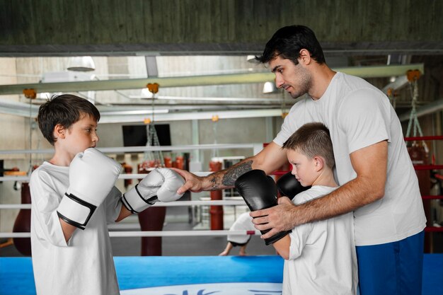 Vista lateral niños aprendiendo boxeo.