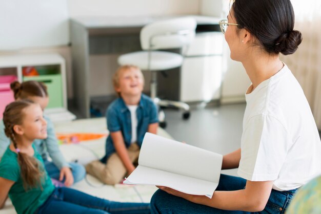 Vista lateral de los niños desenfocados prestando atención a su maestro