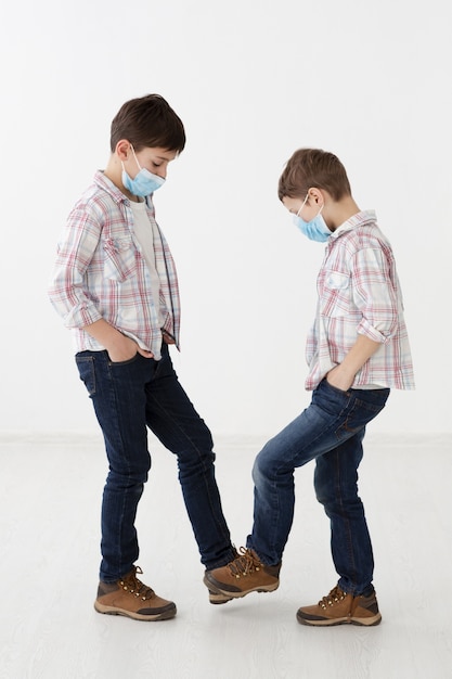 Foto gratuita vista lateral de niños con máscaras médicas que muestran saludos sin contacto