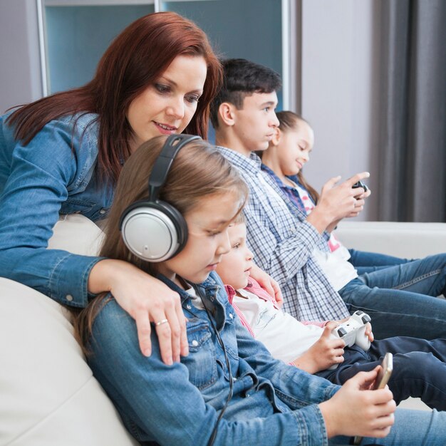 Vista lateral niños con tecnologías y madre