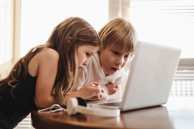 Vista lateral de niños usando laptop juntos