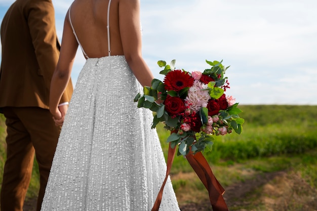 Vista lateral de la novia y el novio posando al aire libre