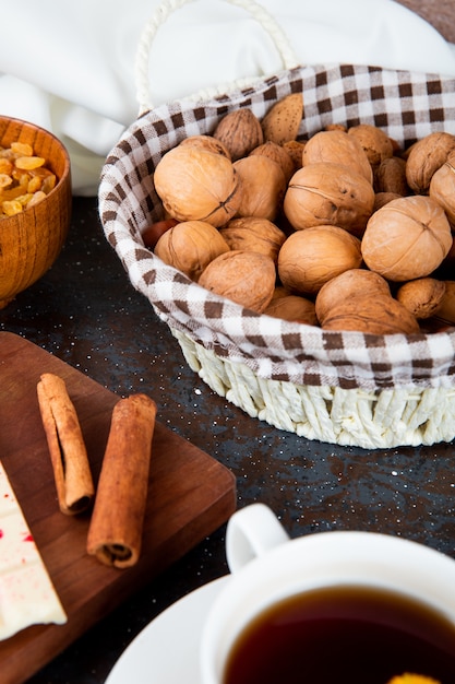 Foto gratuita vista lateral de nueces en una cesta de mimbre y palitos de canela en rústico