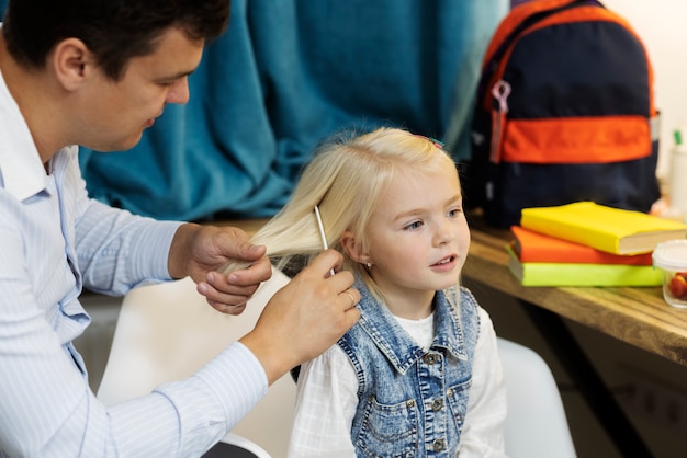 Foto gratuita vista lateral padre cepillando el cabello de la niña para la escuela