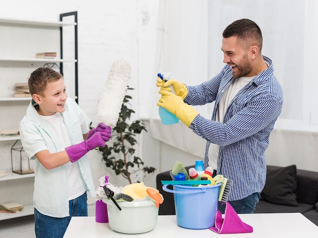 Vista lateral de padre e hijo jugando mientras limpia la casa