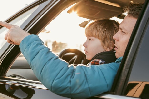 Vista lateral del padre y el niño en el coche durante un viaje por carretera