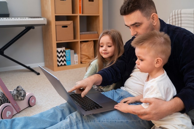 Foto gratuita vista lateral padre trabajando con niños en casa