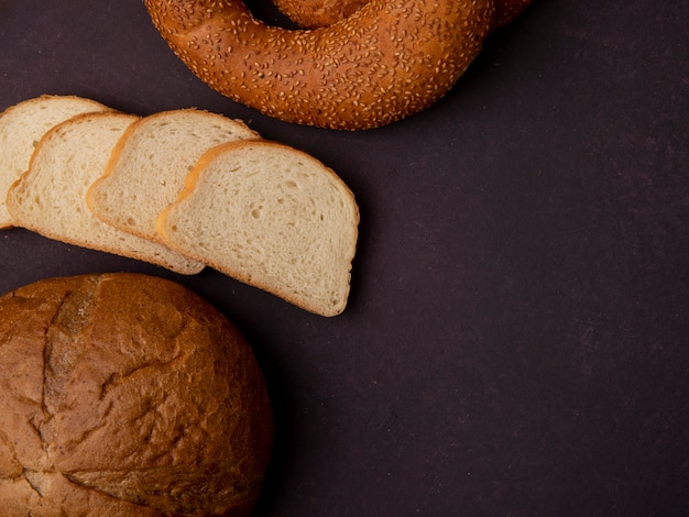 Foto gratuita vista lateral de panes como rebanadas de pan blanco de mazorca clásico y bagel sobre fondo marrón con espacio de copia
