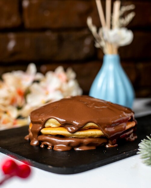 Vista lateral de panqueque con mantequilla de chocolate sobre una tabla para cortar madera