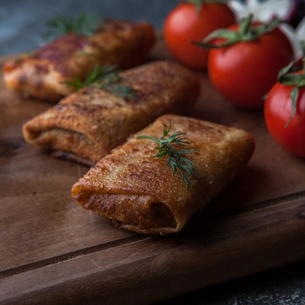 Vista lateral de panqueques con verduras y tomate y rábano en tabla de cortar