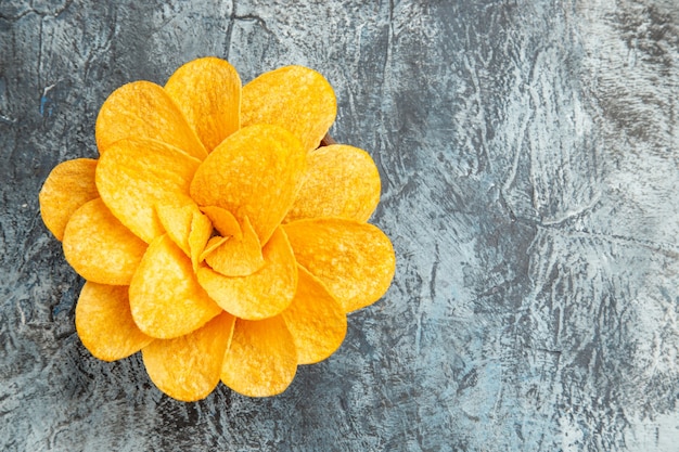 Vista lateral de papas fritas decoradas con forma de flor en un recipiente marrón sobre mesa gris