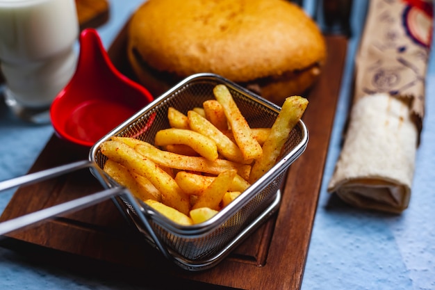 Vista lateral papas fritas con salsa de tomate y hamburguesa en un tablero