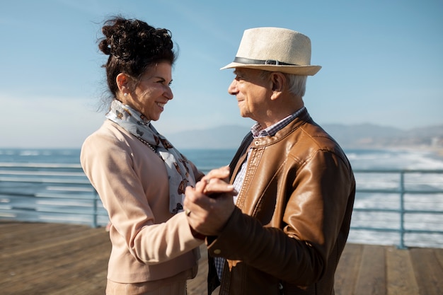 Vista lateral de la pareja de ancianos bailando en el compañero mientras está en una cita