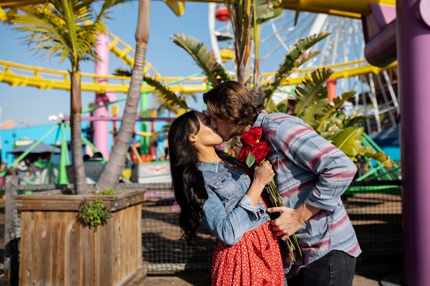 Vista lateral de una pareja besándose en una cita en el parque de diversiones