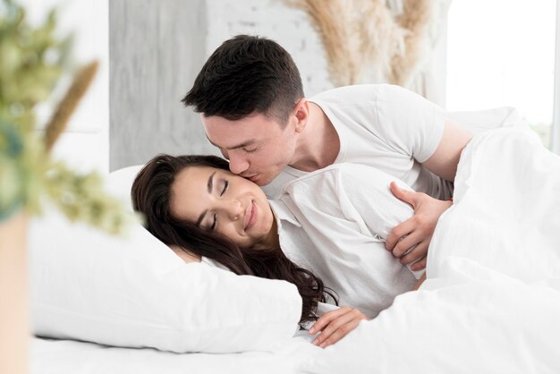 Vista lateral de la pareja en la cama siendo romántico