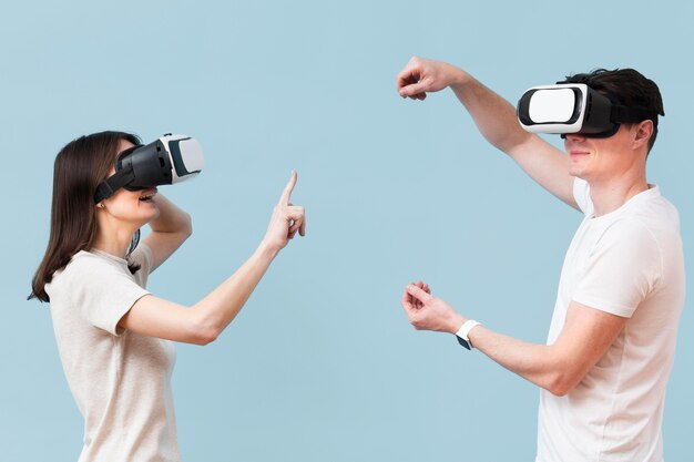 Vista lateral de la pareja divirtiéndose con casco de realidad virtual