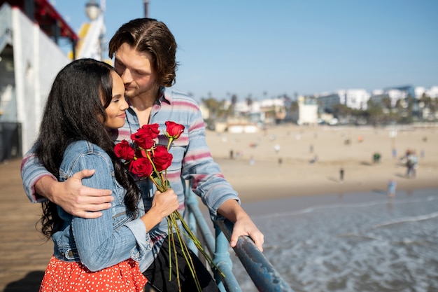 Foto gratuita vista lateral de una pareja joven en una cita en la playa mirando al compañero