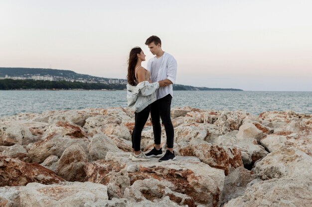 Vista lateral de la pareja romántica abrazada por el océano