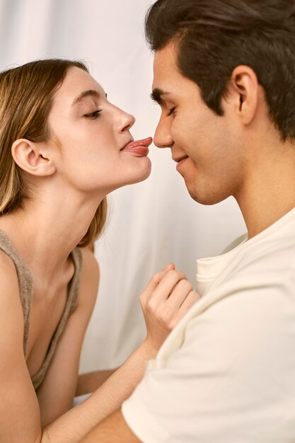 Vista lateral de la pareja sonriente abrazada con mujer sacando la lengua
