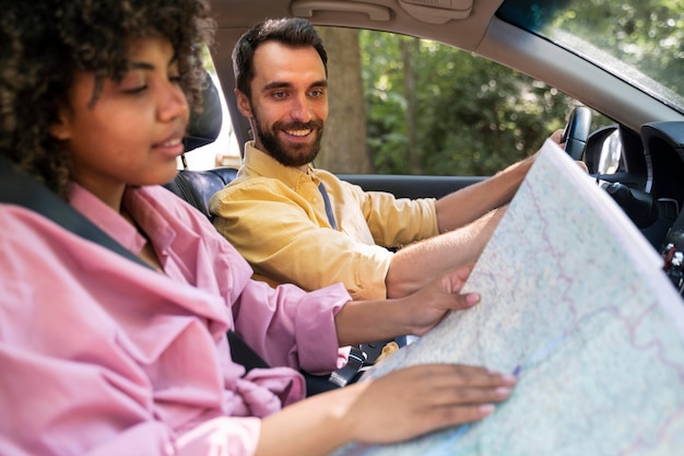 Vista lateral de la pareja sonriente en el mapa de consultoría de automóviles