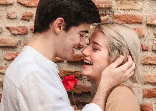 Vista lateral de la pareja sonriente con rose