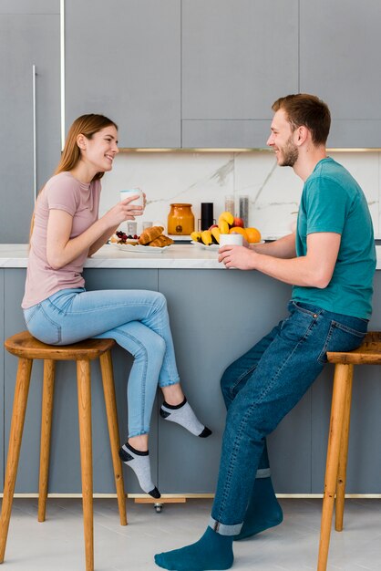 Vista lateral de la pareja sosteniendo la taza en la cocina