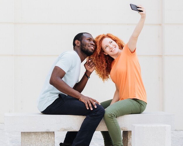 Vista lateral de la pareja tomando un selfie.
