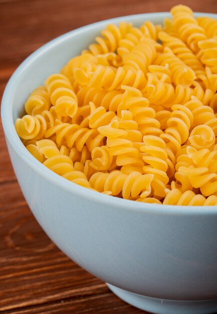 Vista lateral de pasta mafalda en un tazón en la mesa de madera