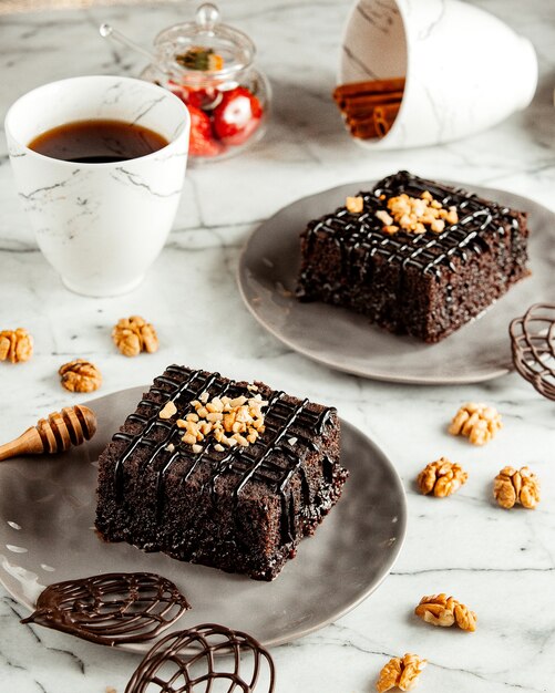 Vista lateral de pasteles de brownie de chocolate en un plato servido con té en la mesa de mármol
