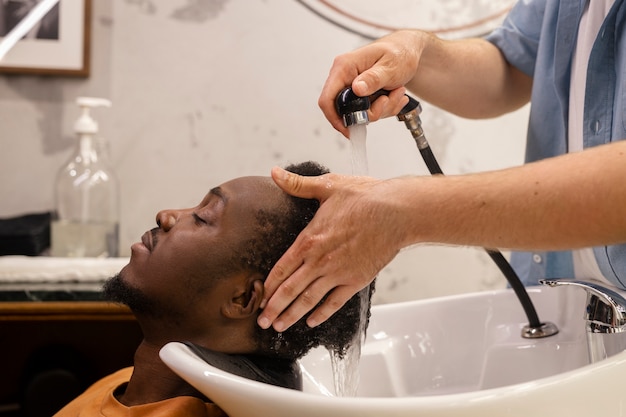 Foto gratuita vista lateral peluquero lavando el cabello del hombre