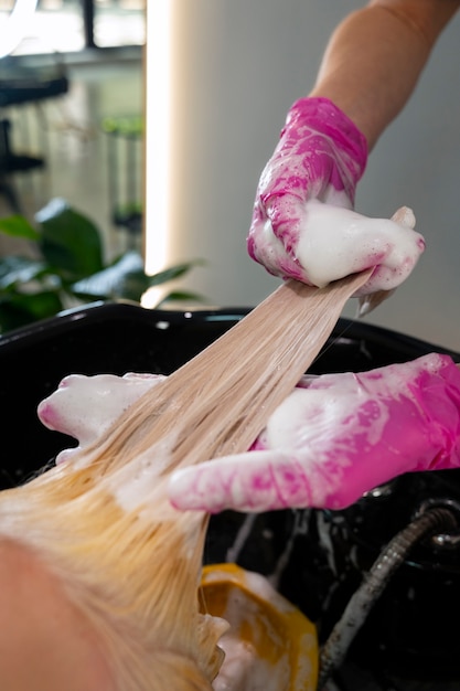 Vista lateral peluquero lavando el cabello de la mujer