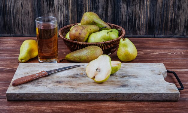 Vista lateral de peras maduras frescas y mitades en una tabla de cortar de madera con cuchillo de cocina sobre fondo rústico