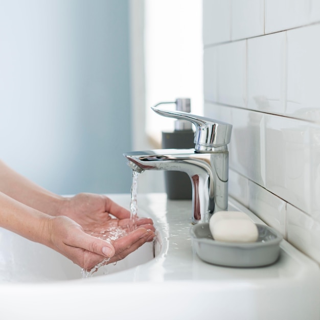 Vista lateral de la persona que se prepara para lavarse las manos en el fregadero