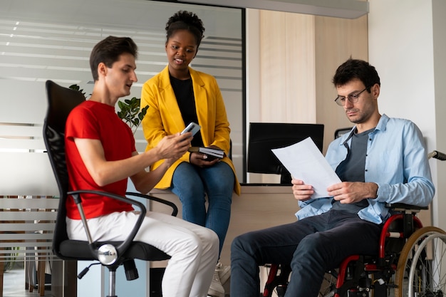 Foto gratuita vista lateral de personas inclusivas en el trabajo.