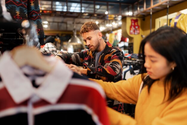 Vista lateral de personas mirando ropa en una tienda de segunda mano