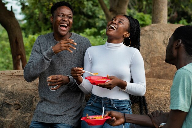 Vista lateral de personas sonrientes almorzando al aire libre