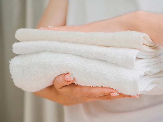 Vista lateral pila de toallas entre manos