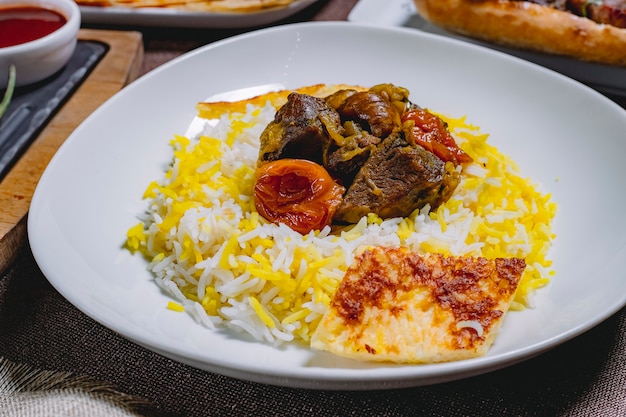 Vista lateral pilaf agria carne frita con castañas de cebolla frutas secas y pastel en un plato